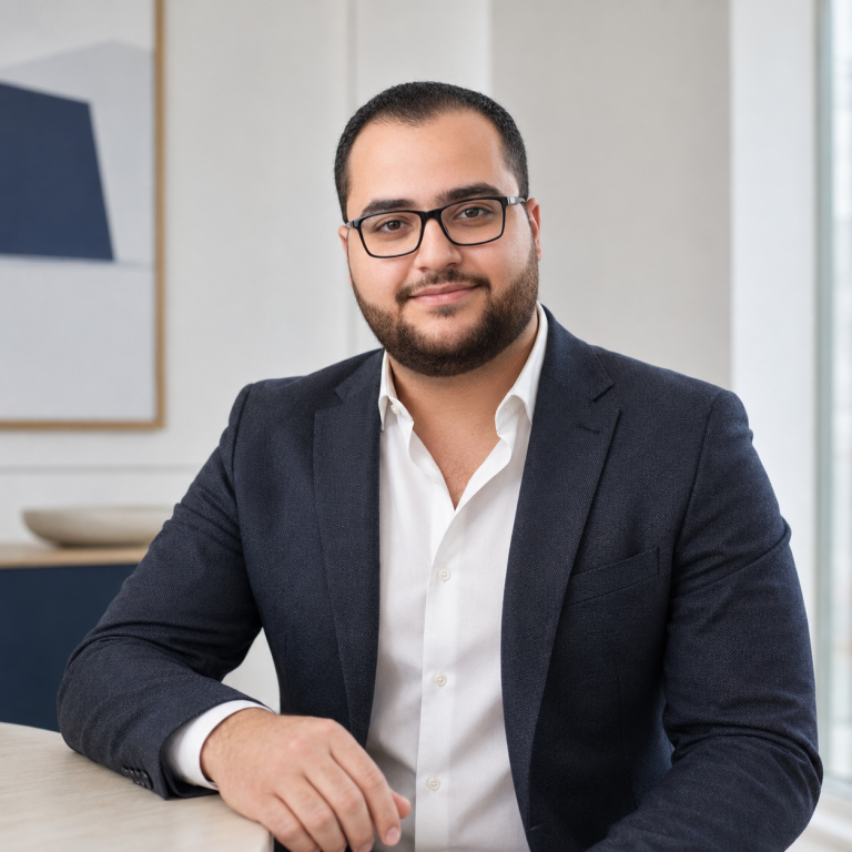 Hamdy, founder of Starbridge Talent, wearing glasses and a dark blue blazer, seated at a table in a bright office